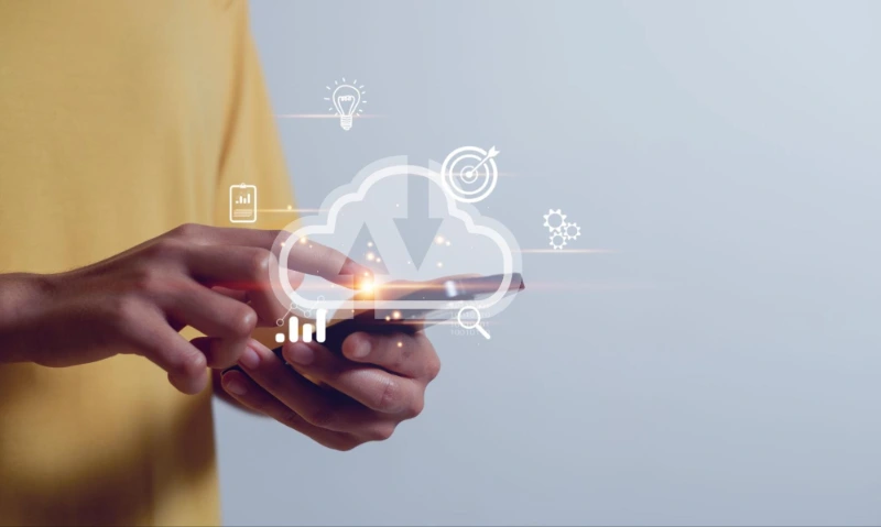 Person in gelbem Shirt nutzt Smartphone, darüber schwebt ein Cloud-Symbol mit Technik-Icons wie Grafiken und Glühbirnen.